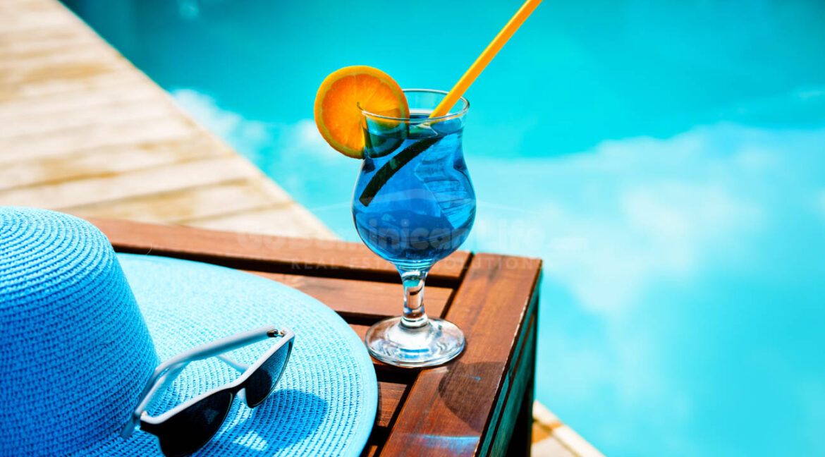Summer,Hat,,A,Cocktail,And,Sunglasses,Near,The,Luxurious,Pool